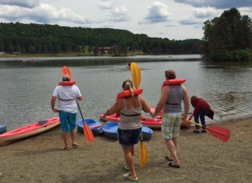A group of people standing on a beach in Western New York, with kayaks.