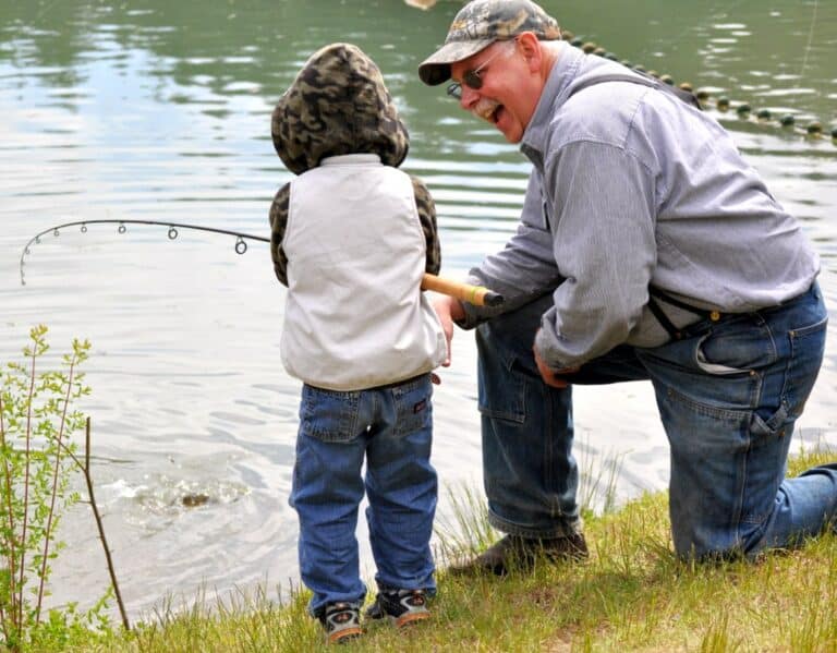 A man is fishing with a little boy at a RV campground in western New York.