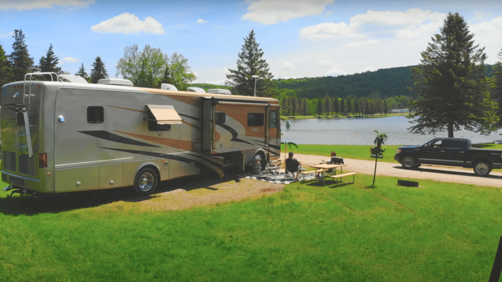 A Rainbow Lake campground with an RV parked near a grassy area.