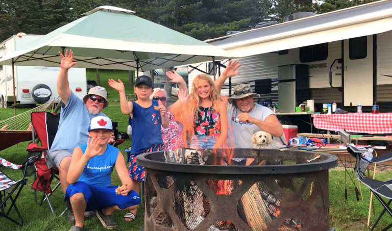 A group of people gathered around a campfire at a campground in Western New York, enjoying the experience of camping.