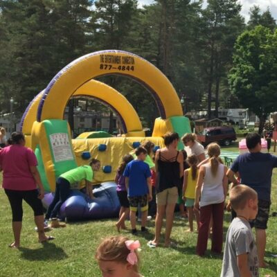 People enjoying an inflatable obstacle course at a Rainbow Lake RV resort.