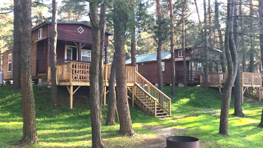 Two rustic cabins in a wooded setting, reached by a short flight of stairs