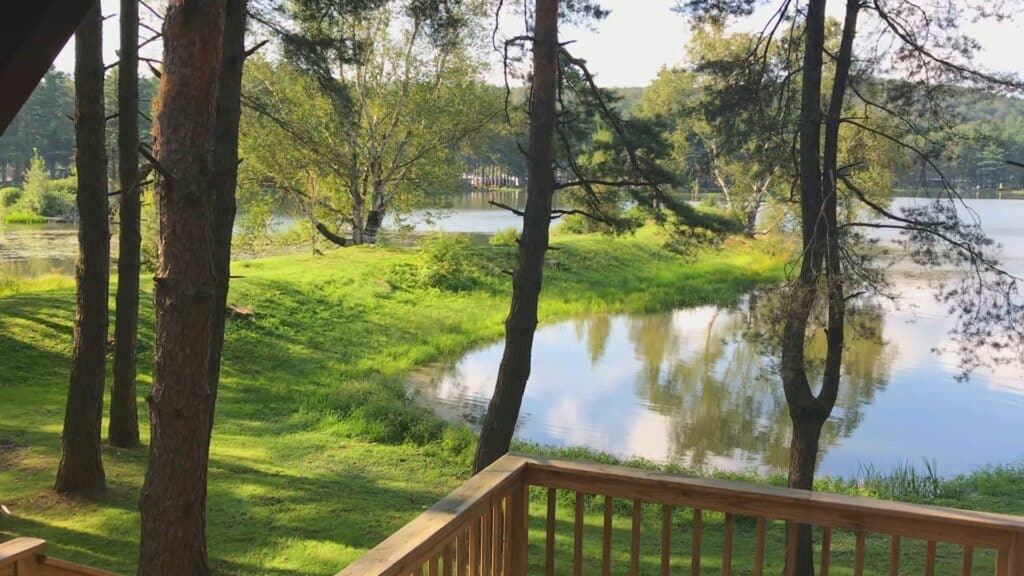 A serene view of Rainbow Lake from a deck in a wooded area, ideal for or cabin stays at the resort.