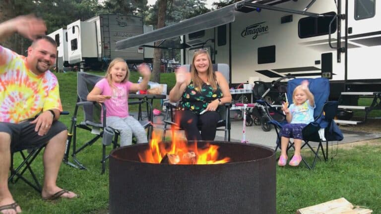 A family enjoys camping in front of their RV at a family campground.