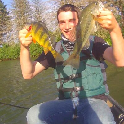 A man holding up two fish at a family campground.