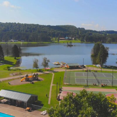An aerial view of a tennis court situated by a serene lake.