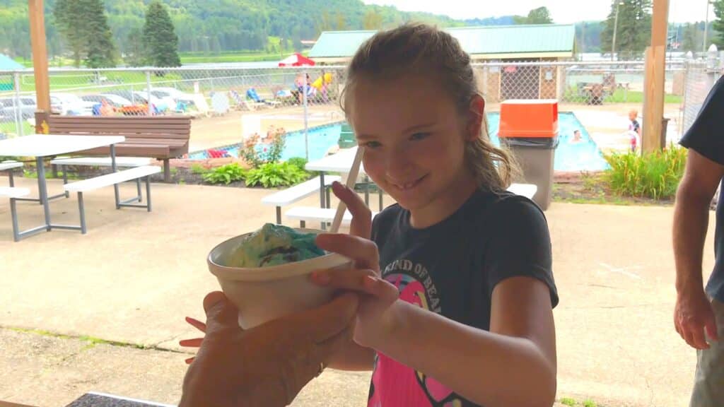 A young girl is holding a cup of ice cream at a cabin in an RV campground.
