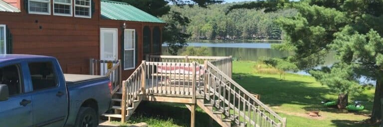 A cabin with a deck and ramp overlooking Rainbow Lake
