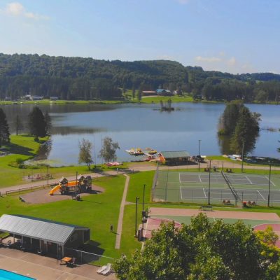 An aerial view of a tennis court situated by a serene lake.