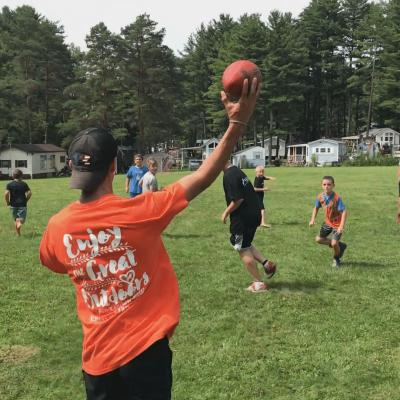 A group of people playing a game of football in a campground field.